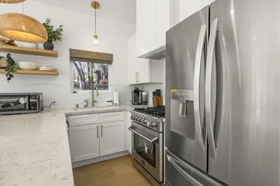 a kitchen with a stainless steel refrigerator and white cabinets at Skyline Summit Lodge in Big Bear Lake