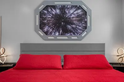 a bedroom with a red bed with a window above it at Star Wars Retreat by OC Adventure Homes in Garden Grove