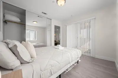 a white bedroom with a large bed with white pillows at Niagara Haven Unit 103 in Burbank