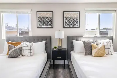 two beds in a bedroom with two windows at Modern 4BR Stay Premium Beds & Full Kitchen in Burbank