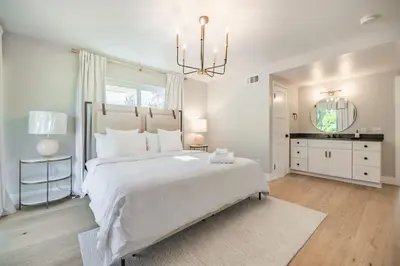 a white bedroom with a large bed and a chandelier at Cozy Modern Haven w Soothing Ambience & Pool in Fullerton