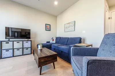 a living room with a blue couch and a table at Luxury 1BD Condo in LA with Rooftop City Views, Gym & Free Parking in Los Angeles