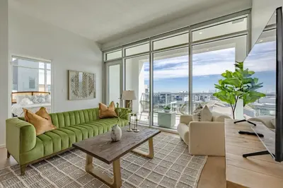 a living room with a green couch and large windows at Marbella Lane - Sleek Corner Ocean View in Long Beach
