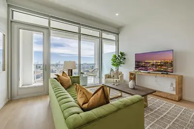 a living room with a green couch and large windows at Marbella Lane - Sleek Corner Ocean View in Long Beach