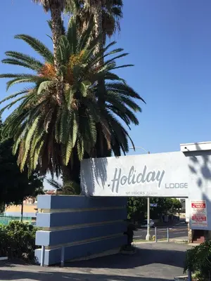 a sign for a holiday store with a palm tree at Holiday Lodge in Los Angeles