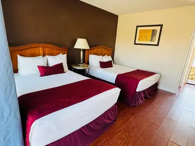 a hotel room with two beds with red sheets at Holiday Lodge in Los Angeles