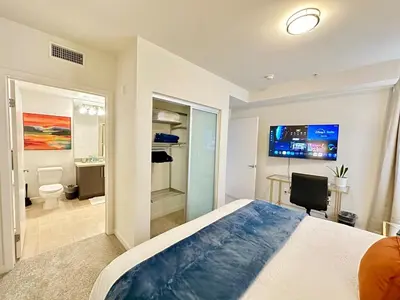 a bedroom with a bed and a bathroom with a tv at 5 Star Location with City Views 2BD 2BA with King Beds in Los Angeles