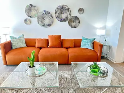 an orange couch in a living room with mirrors at 5 Star Location with Open City Views 2BD 2BA with King Beds in Los Angeles