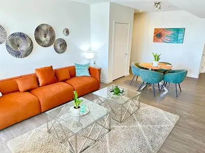 a living room with an orange couch and a table at 5 Star Location with Open City Views 2BD 2BA with King Beds in Los Angeles