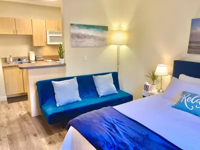 a living room with a blue couch and a kitchen at Fully Equipped DTSM Studio, Blocks to Ocean & Pier in Los Angeles