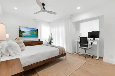 a white bedroom with a bed and a desk at Moonstone Beach House Oceanview Luxe Retreat in Manhattan Beach