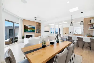 a dining room and living room with a wooden table and chairs at Moonstone Beach House Oceanview Luxe Retreat in Manhattan Beach