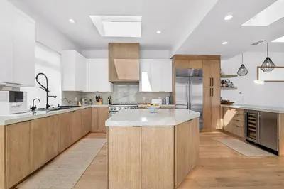 a large kitchen with wooden cabinets and white appliances at Moonstone Beach House Oceanview Luxe Retreat in Manhattan Beach