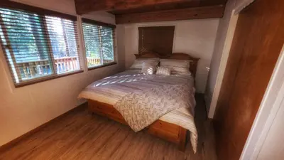 a bed in a room with two windows at Cozy Cabin Retreat with a Hot Tub in Running Springs