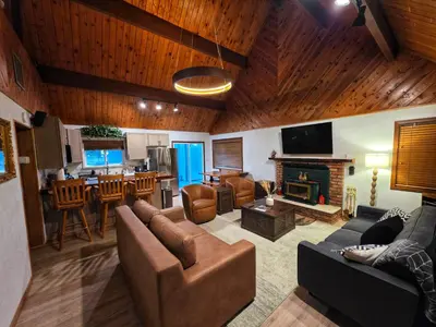 a living room with a couch and a fireplace and a kitchen at Cozy Cabin Retreat with a Hot Tub in Running Springs