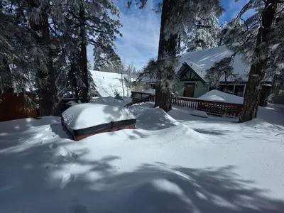 a yard covered in snow with a house at Cozy Cabin Retreat with a Hot Tub in Running Springs