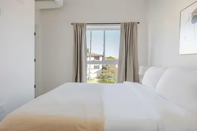 a white bedroom with a large bed and a window at Blueground East Hollywood rooftop nr Griffith Park LAX-1335 in Los Angeles