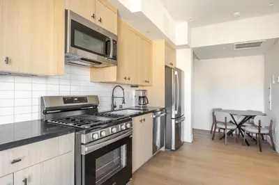 a kitchen with stainless steel appliances and a table at Blueground East Hollywood rooftop nr Griffith Park LAX-1335 in Los Angeles