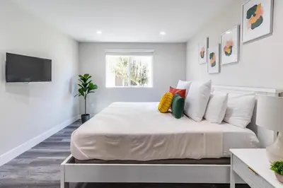 a white bedroom with a large bed and a tv at Escape in Modern 4BR Home Sleeps 10 with Parking in Burbank