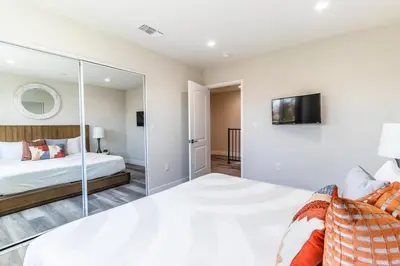 a bedroom with a large white bed and a mirror at Escape in Modern 4BR Home Sleeps 10 with Parking in Burbank