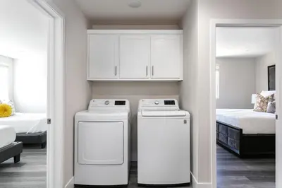 two washing machines in a small room with a bed at Spacious Home Central Area Airport Free Parking in Burbank