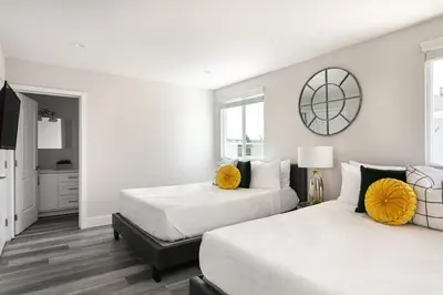 two beds in a bedroom with white walls and yellow pillows at Spacious Home Central Area Airport Free Parking in Burbank