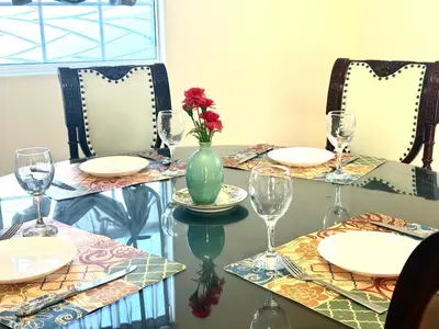 a table with plates and glasses and a vase with flowers on it at Spacious 3BR 3BA Home 3 Car Garage Garden Near DTLA Pasadena Hollywood in Alhambra
