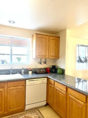 a kitchen with wooden cabinets and a white dishwasher at Spacious 3BR 3BA Home 3 Car Garage Garden Near DTLA Pasadena Hollywood in Alhambra