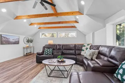 a living room with a leather couch and a table at Tall Pines Retreat Large Patio w BBQ and Firepit! in Big Bear City Airport