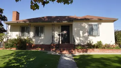 a white house with a front door and a lawn at \u963f\u5c14\u7f55\u5e03\u62c9\u6c11\u5bbf in Alhambra