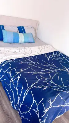 a bed with a blue comforter with branches on it at Huge bedroom with shared bathroom in Ontario
