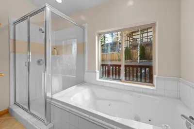 a white bathroom with a tub and a window at Pine Cottage - NEW! Shuffleboard, Pool Table, Smart TVs, Fenced Yard in Big Bear Lake