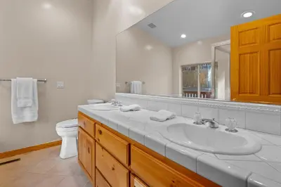 a white bathroom with a sink and a toilet at Pine Cottage - NEW! Shuffleboard, Pool Table, Smart TVs, Fenced Yard in Big Bear Lake