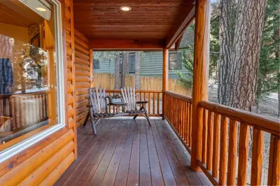 a porch of a wooden cabin with a rocking chair at Pine Cottage - NEW! Shuffleboard, Pool Table, Smart TVs, Fenced Yard in Big Bear Lake