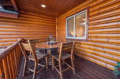 a dining room with a table and chairs on a deck at Pine Cottage - NEW! Shuffleboard, Pool Table, Smart TVs, Fenced Yard in Big Bear Lake