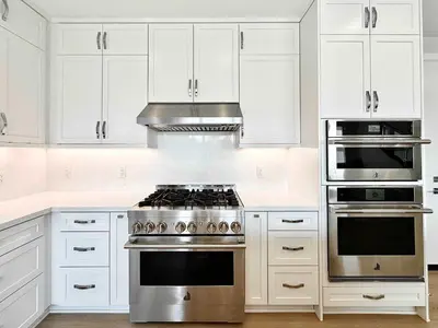 a kitchen with white cabinets and a stainless steel stove at Marbella Lane Spacious 4BR Modern Family Home in Placentia