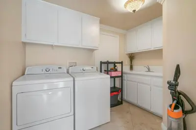 a kitchen with white cabinets and a washer and dryer at Marbella Lane - Captivating Home w Pool in Rowland Heights