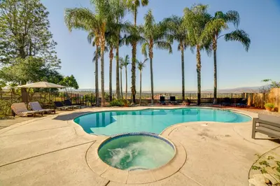 a swimming pool with palm trees in the background at Spacious Riverside Farmhouse, Perfectly Located in Riverside