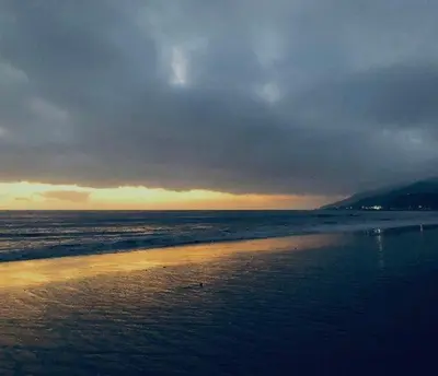 a beach with a cloudy sky and the ocean at Villa Porto Marina - Oceanfront Living in Castellammare