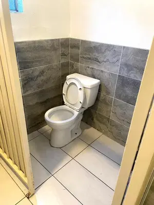 a bathroom with a toilet and a tiled wall at AVAION HOTEL LAX SoFi STADIUM in Inglewood