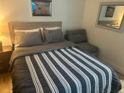 a bed with a striped blanket and a chair in a room at Minimalist Room in Buena Park in Buena Park