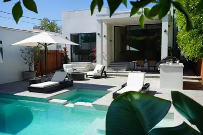 a pool with chairs and an umbrella next to a house at The Hollywood House in Los Angeles