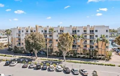 an apartment building with cars parked in a parking lot at The Nautilus Waterfront Retreat Marina View, Pool Sauna Gym Jacuzzi in Los Angeles