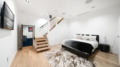 a white bedroom with a bed and a staircase at Hollywood Hills 6BR Luxury Home w Pool, Theater & Panoramic Views in Los Angeles
