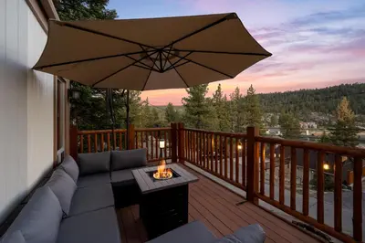 a patio with a couch and an umbrella on a deck at Lakeview Bear Cubs Den - Walk to Lake, Close to Slopes in Big Bear Lake