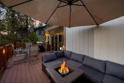 a patio with a couch and an umbrella at Lakeview Bear Cubs Den - Walk to Lake, Close to Slopes in Big Bear Lake