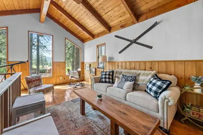 a living room with a couch and a clock on the wall at Colibri Cabin - Walk to Lake and Trails in Big Bear Lake
