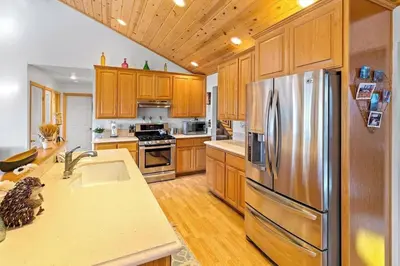 a kitchen with wooden cabinets and a stainless steel refrigerator at Lakeview Retreat - Walk to Lake, Close to Slopes in Big Bear Lake