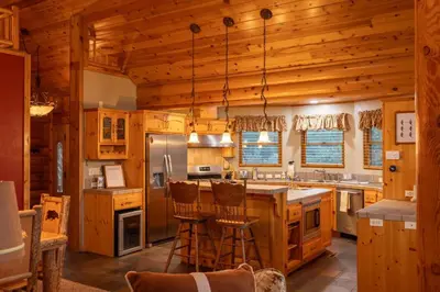 a kitchen with wooden cabinets and a large island with bar stools at Foster’s Cabin - Close to Lake and Slopes in Big Bear City