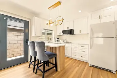 a kitchen with a white refrigerator and two bar stools at Lyn's Stay in Westminster